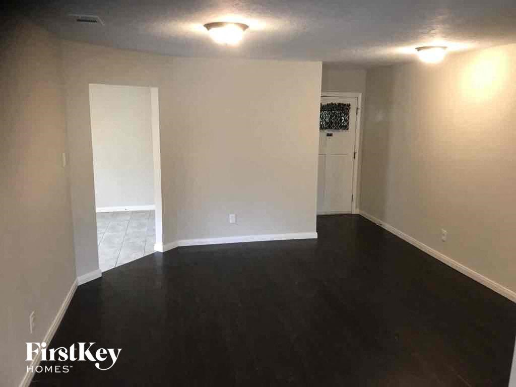 an empty living room with a dark wood floor and white walls