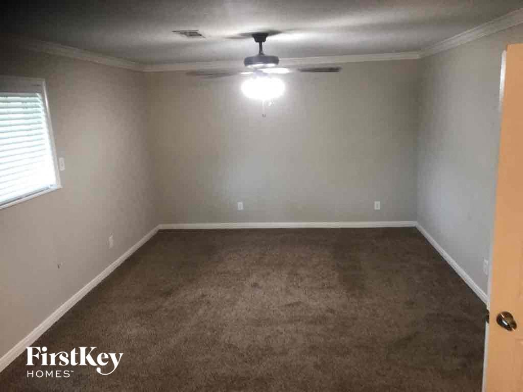 a empty room with a ceiling fan and a carpet