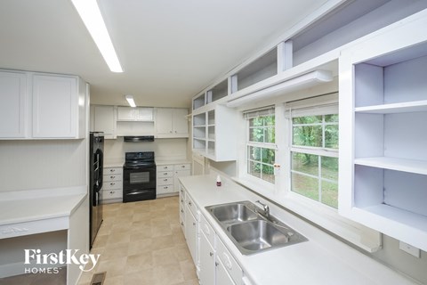 A kitchen with white cabinets and a black fridge.