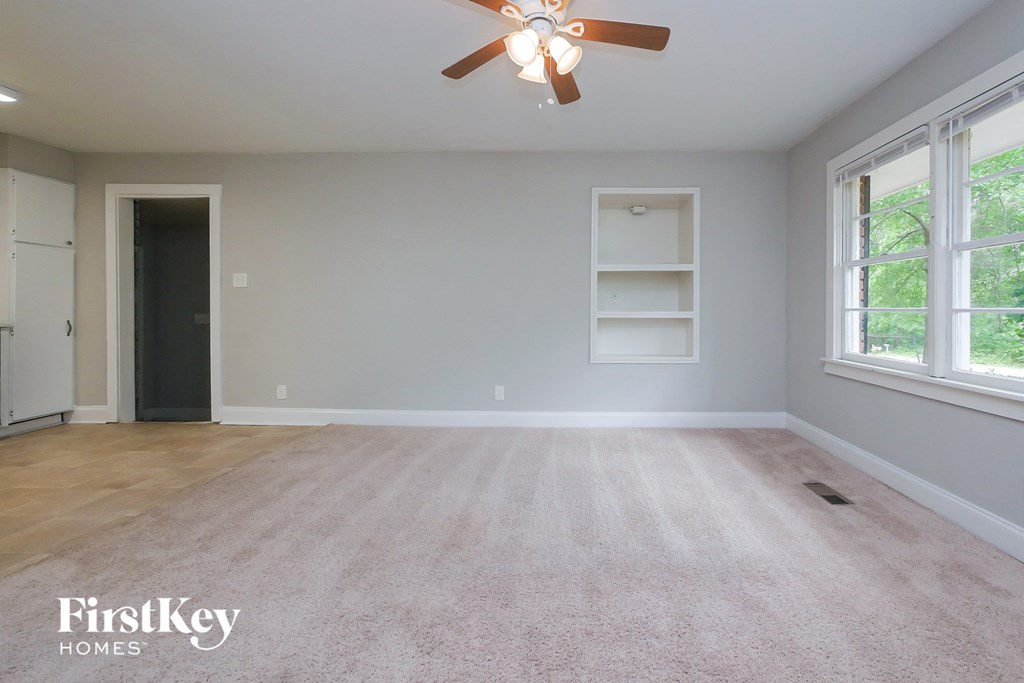 A room with a ceiling fan and a rug on the floor.