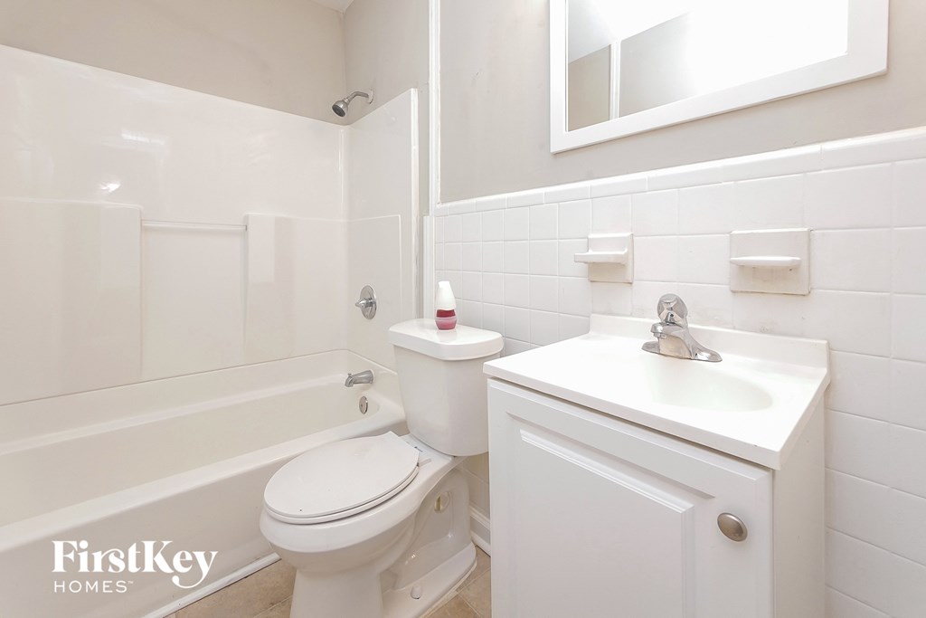 A white bathroom with a toilet, sink, and mirror.