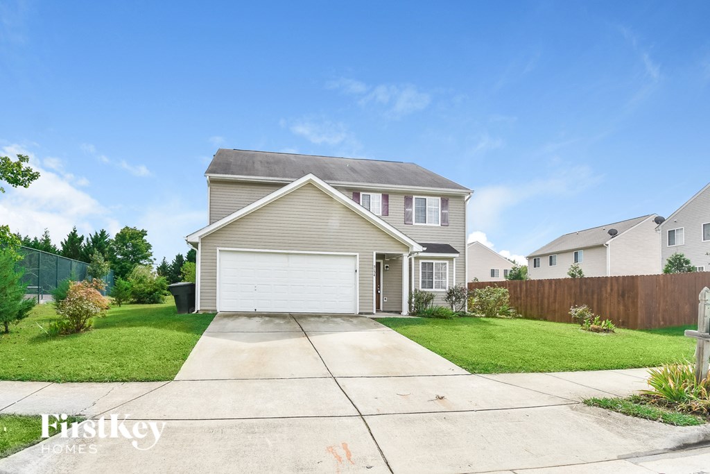 a beige house with a white garage door and a lawn