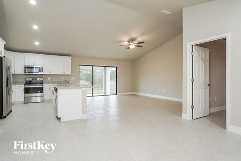 an empty kitchen and living room with a ceiling fan