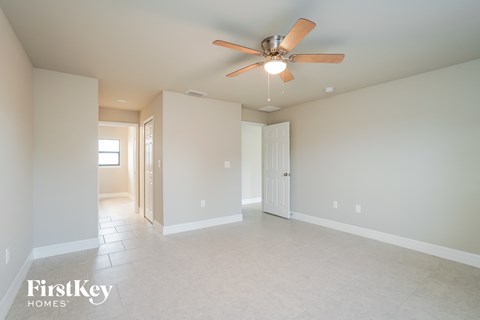a spacious living room with a ceiling fan and white tile floors
