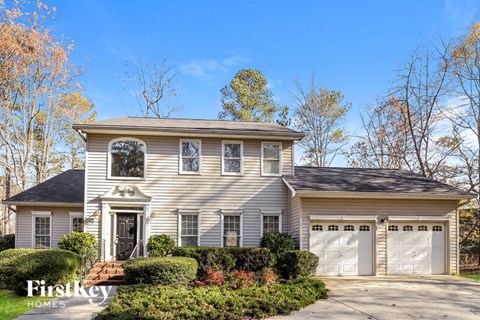 a white house with two garage doors and a driveway