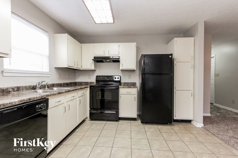 a kitchen with white cabinets and black appliances