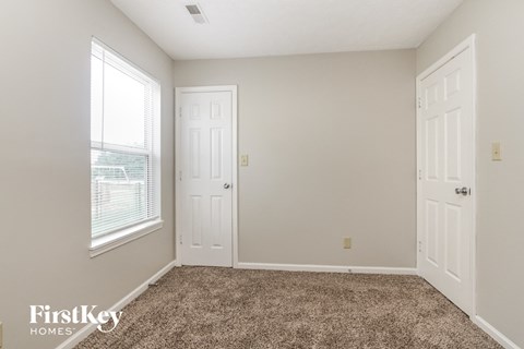 a bedroom with carpet and two doors and a window