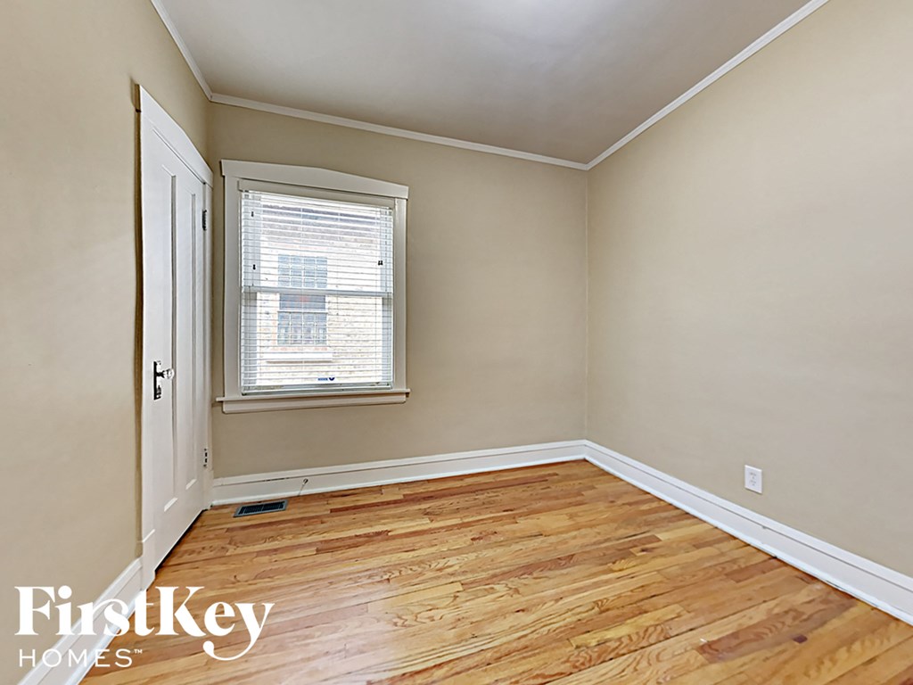 an empty bedroom with wood floors and a window