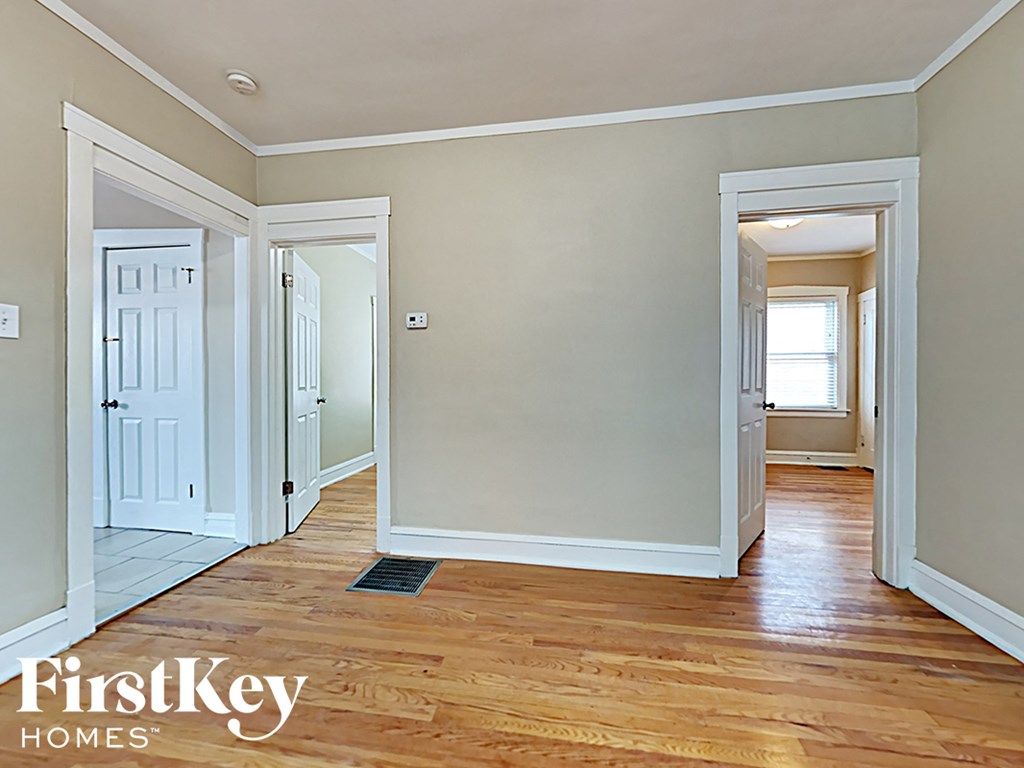 the living room and hallway of an empty house with wood floors
