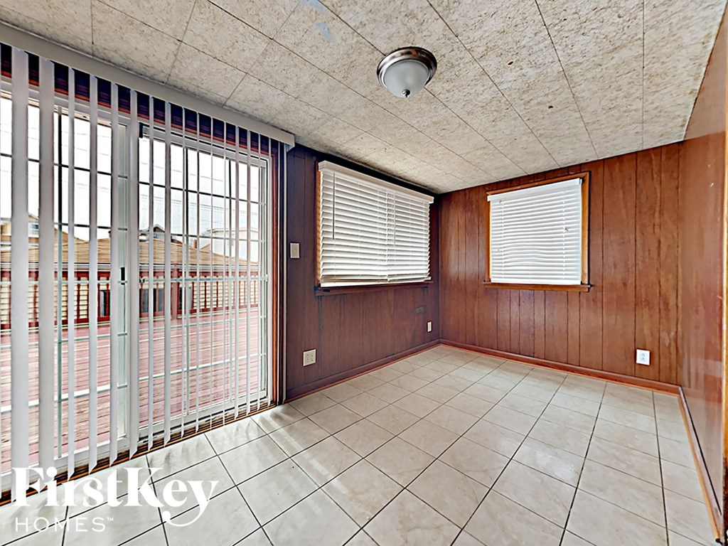 an empty living room with large windows and a tile floor