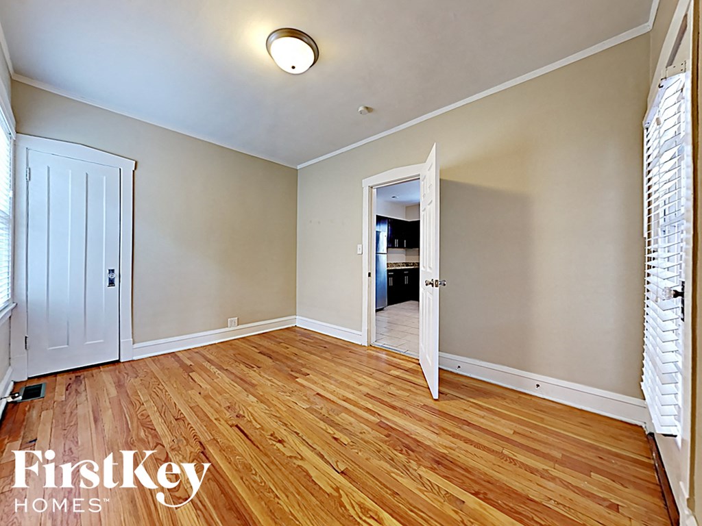 an empty living room with wood flooring and a door to a hallway