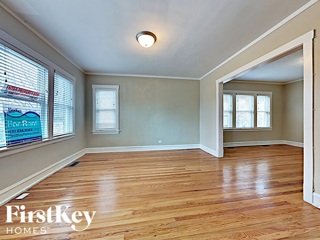 an empty living room with wood floors and a large window