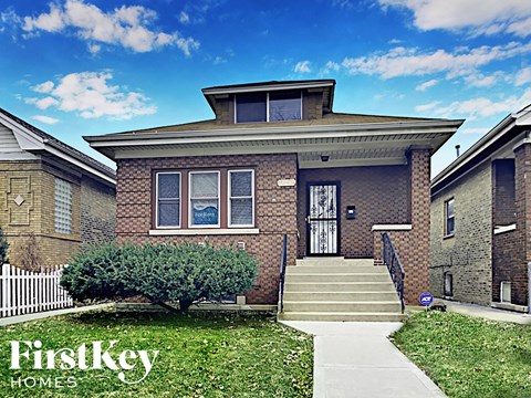 the front of a brick house with a white picket fence