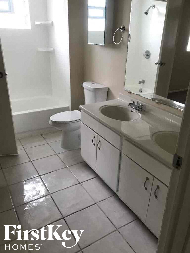 A white bathroom with a toilet, sink and mirror.