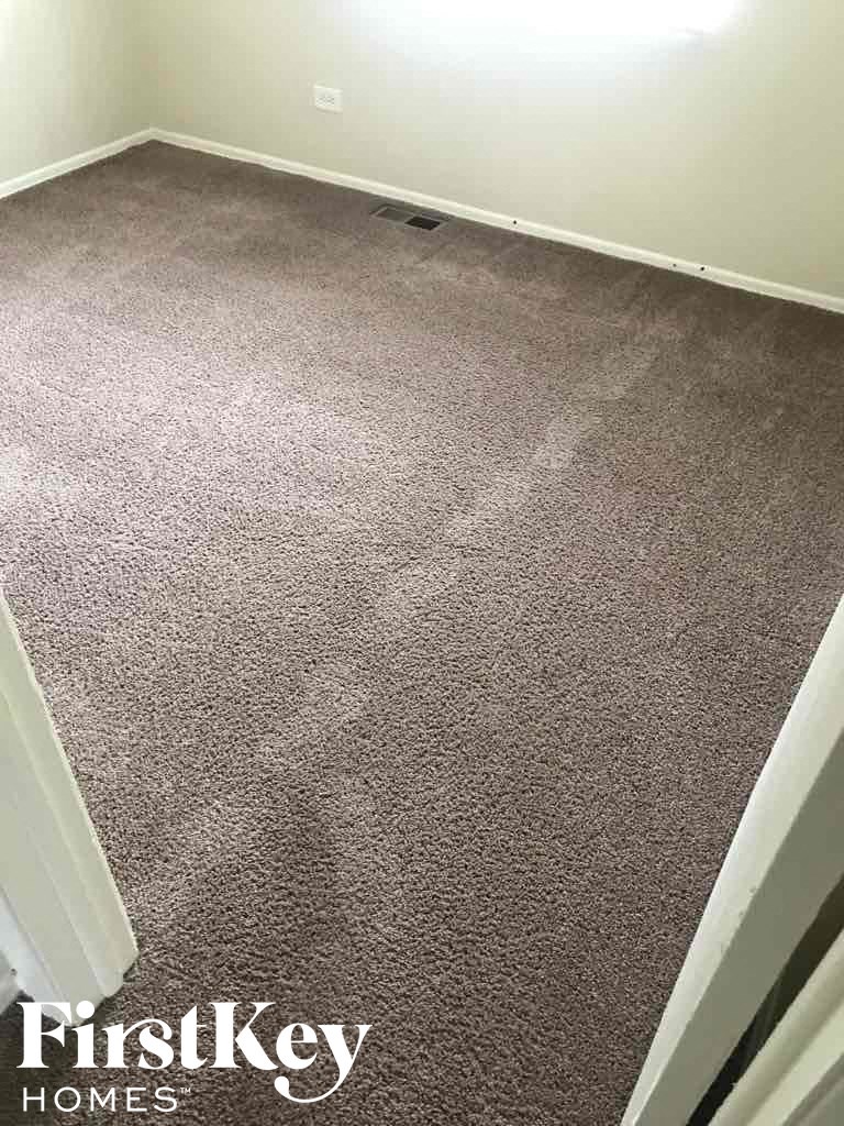 A carpeted room with a FirstKey Homes logo.