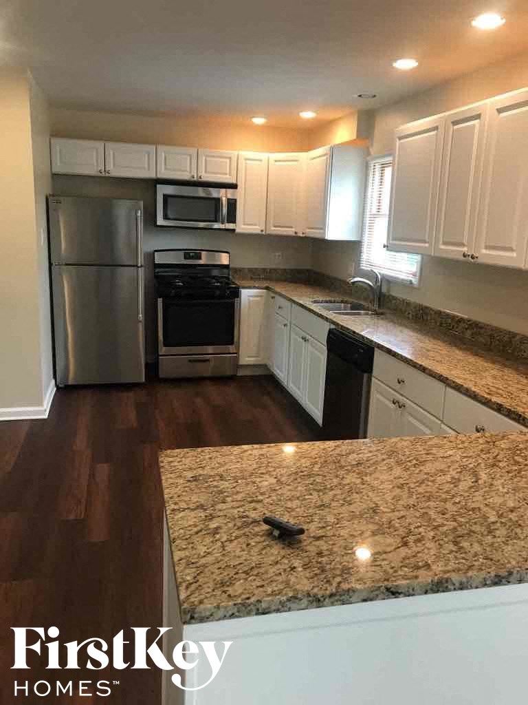 A kitchen with a granite counter top and a refrigerator.