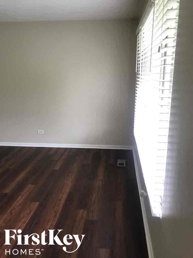 A room with wooden flooring and a window with blinds.