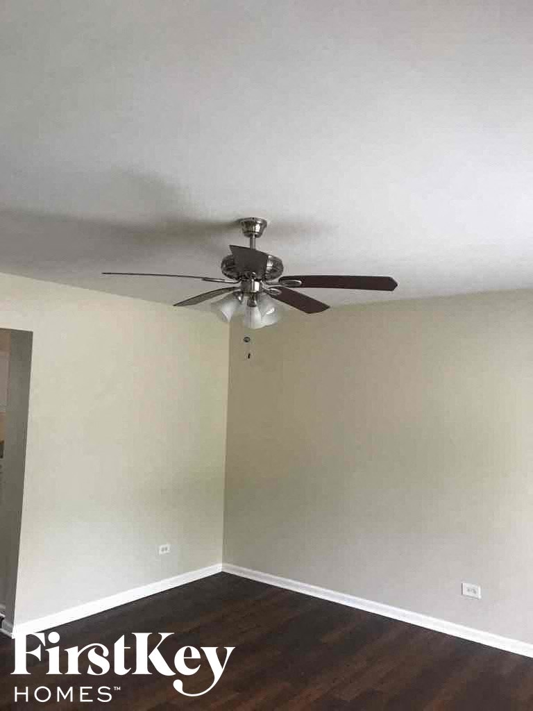 A room with a ceiling fan and wooden floors.