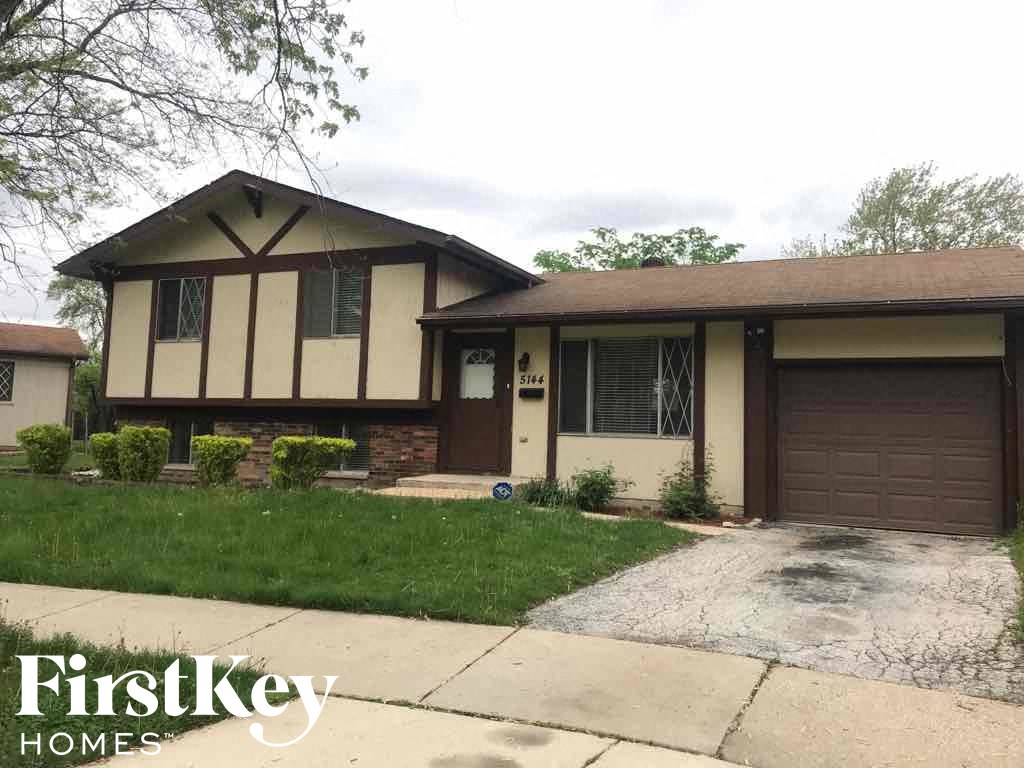 A house with a garage and a driveway in front of it.