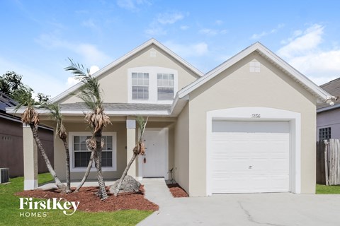 A two-story house with a garage and a driveway in front.
