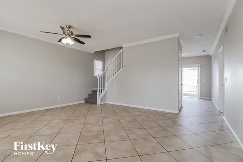 A spacious room with a staircase and a ceiling fan.