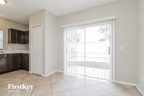A kitchen area with a white door and a sliding glass door leading to a balcony.