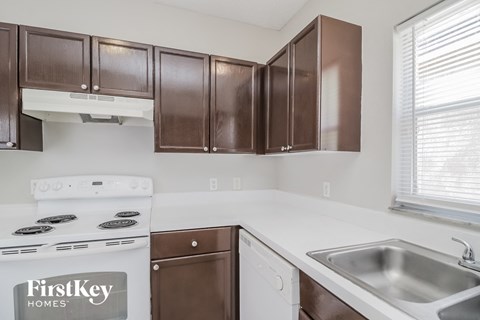 A kitchen with brown cabinets and a stove that says FirstKey Homes.