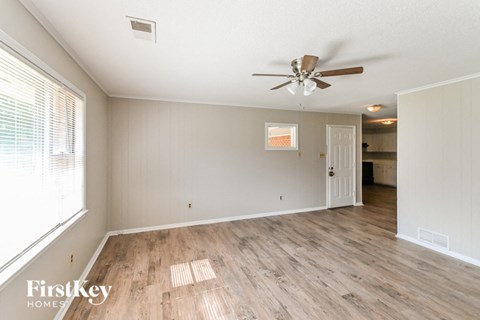 the living room and dining room with wood flooring and a ceiling fan