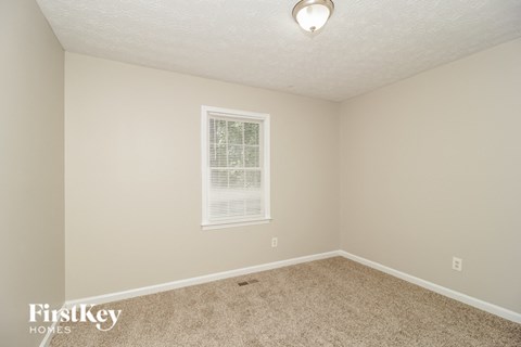 a bedroom with beige carpet and a window