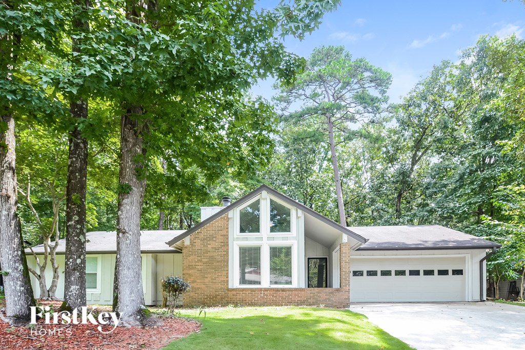 A house with a garage is surrounded by trees.