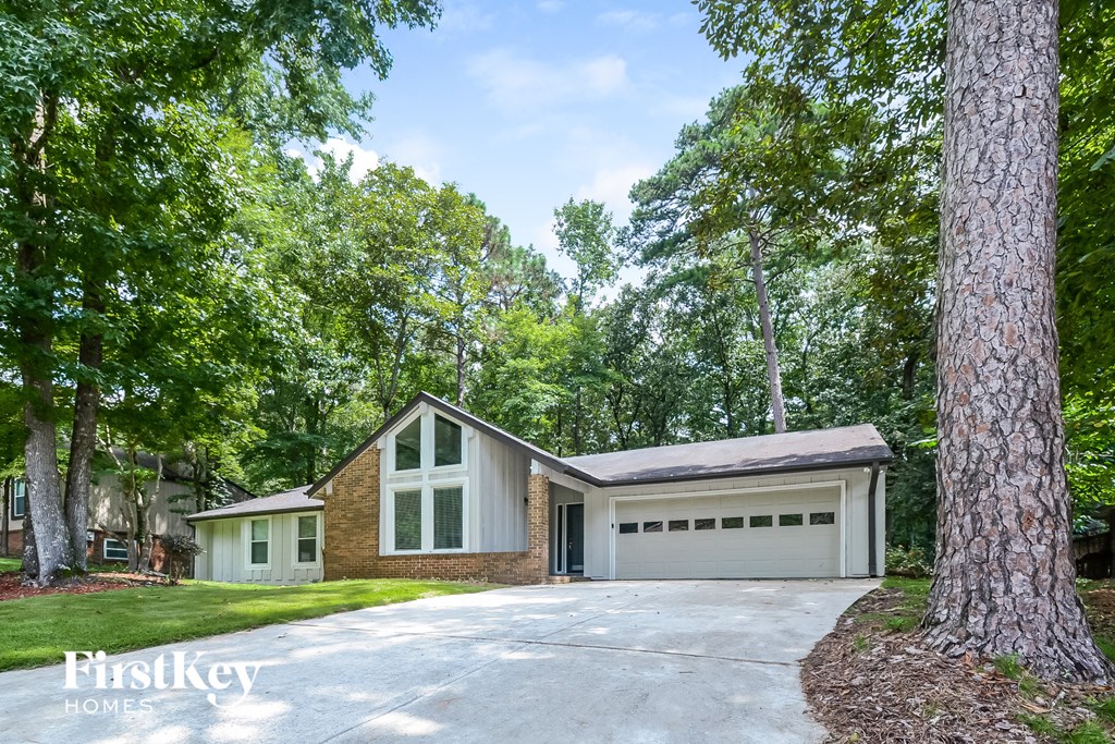 A house with a garage is surrounded by trees.