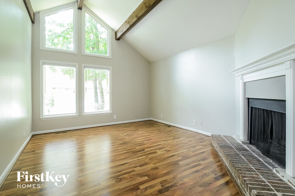 A room with a fireplace and a window with a view of trees.