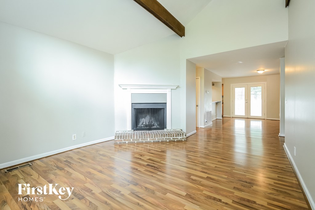 A spacious room with a fireplace and wooden floors.