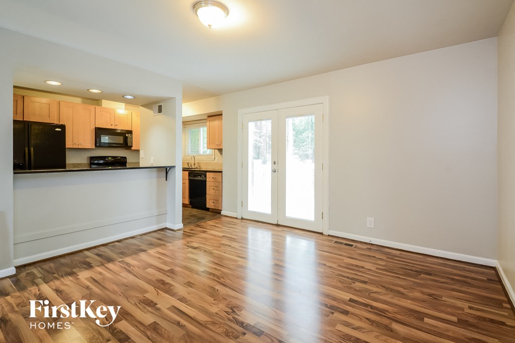 A spacious kitchen and living room with wooden floors and white walls.