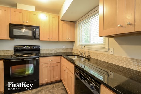 A kitchen with wooden cabinets and black appliances.