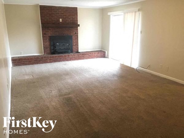 A living room with a fireplace and a carpet.