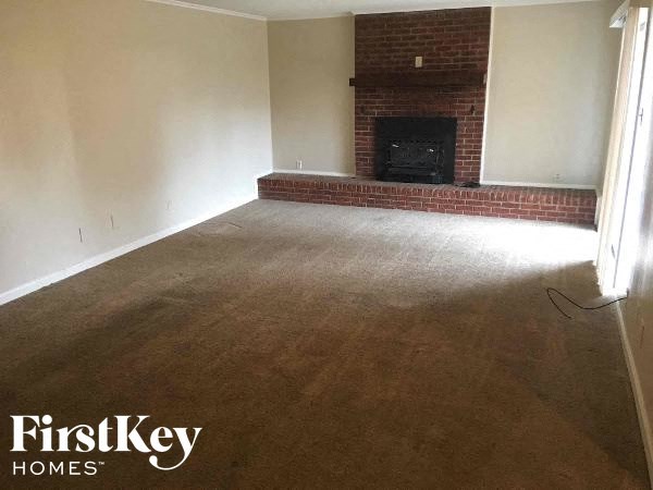 A living room with a fireplace and a carpet.