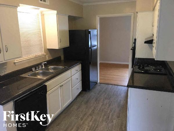 A kitchen with a black counter top and white cabinets.