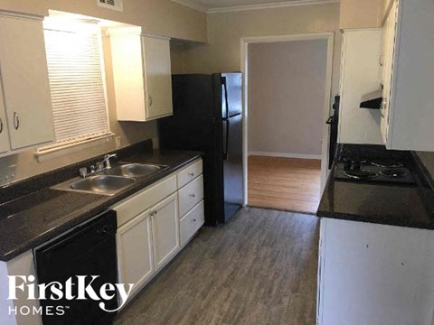 A kitchen with a black counter top and white cabinets.
