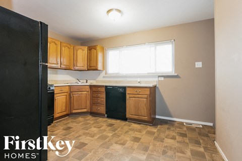 A kitchen with wooden cabinets and a black refrigerator.