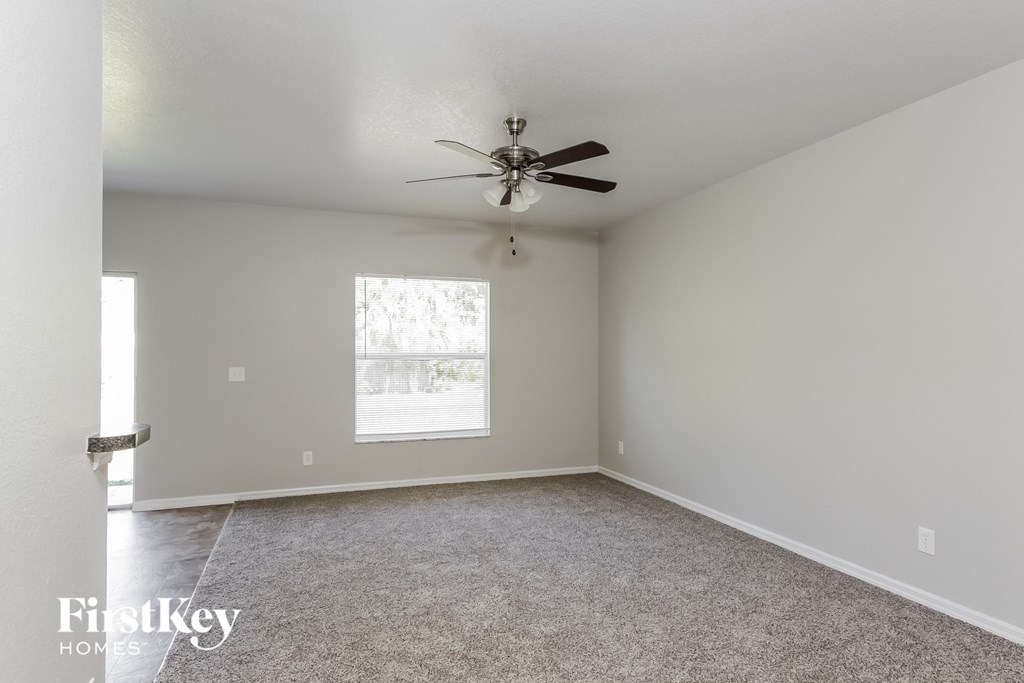 a living room with a ceiling fan and a carpet