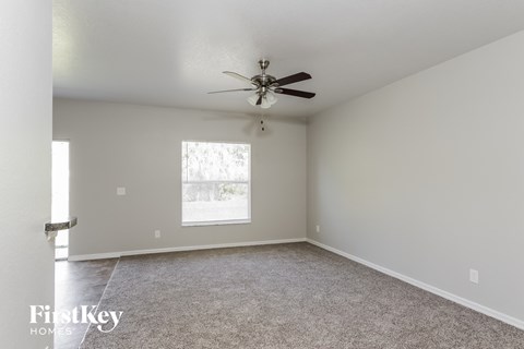 a living room with a ceiling fan and a carpet