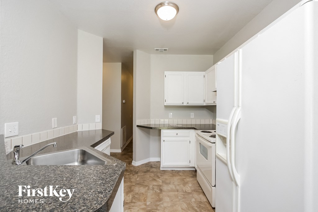 a kitchen with white cabinets and a sink and a refrigerator