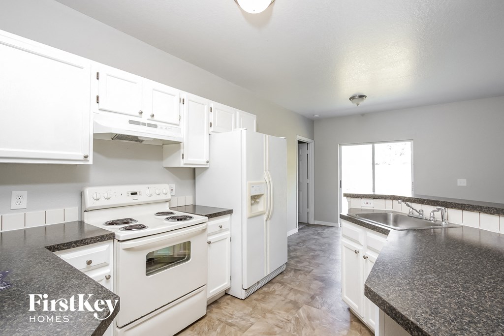 a kitchen with white appliances and white cabinets and granite counter tops