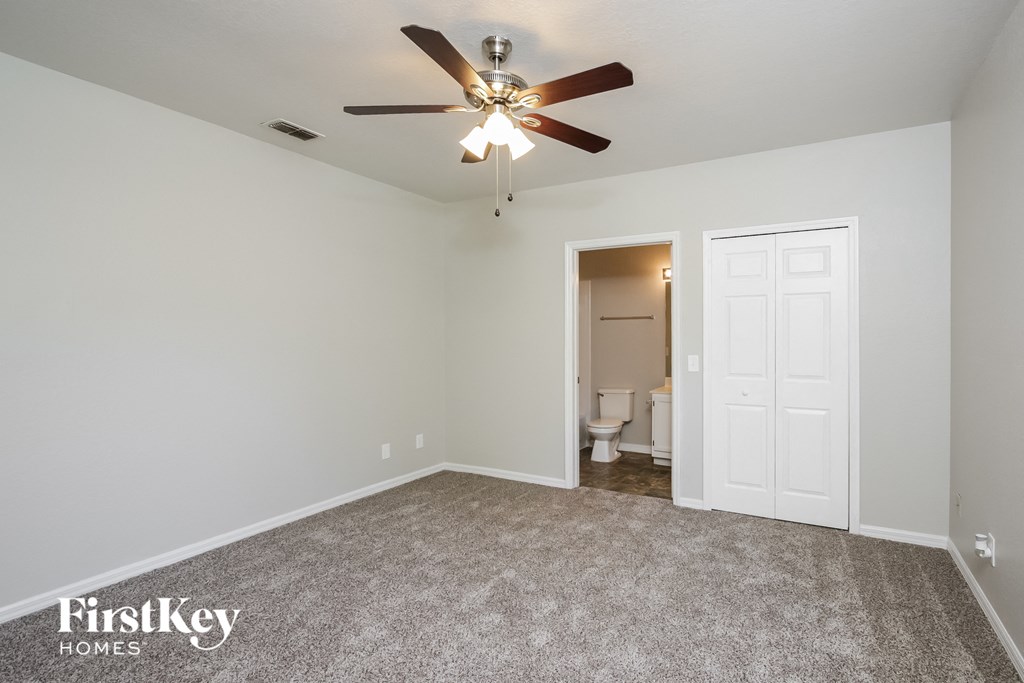 an empty room with a ceiling fan and a door to the bathroom