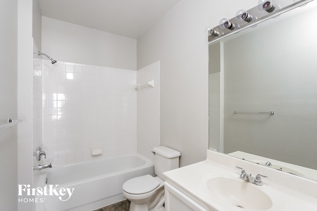 a white bathroom with a tub and a sink and a mirror