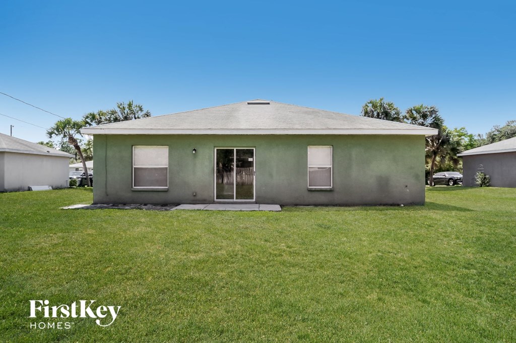 a small gray house with a grass yard and a blue sky