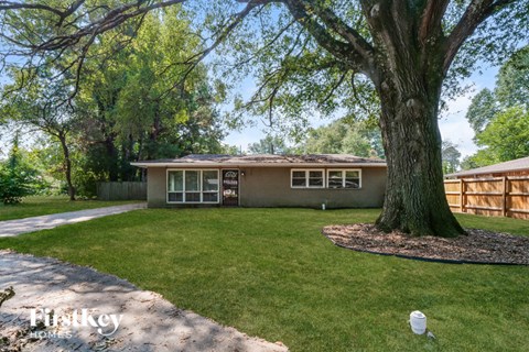 A house with a large tree in front of it.