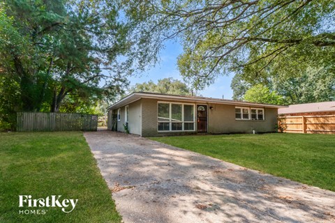A house with a driveway and trees in the background.