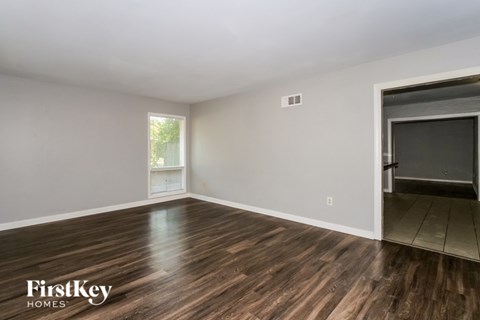 A room with wooden flooring and a sliding door leading to another room.